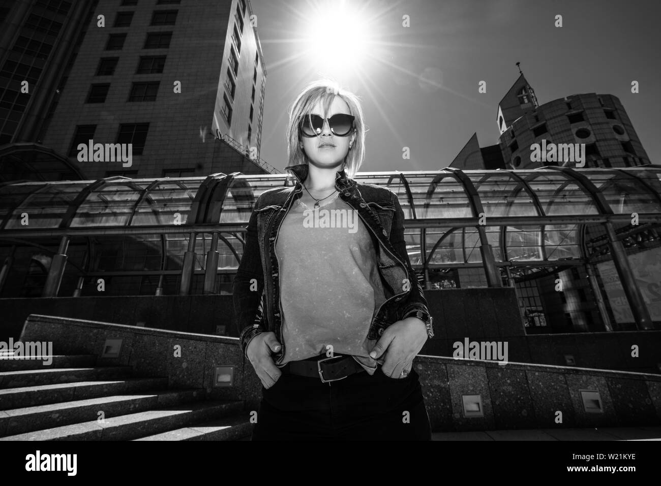 Jeune femme moderne dans les lunettes sur l'arrière-plan de gratte-ciel. La vie dans la ville moderne. La photographie en noir et blanc. Banque D'Images