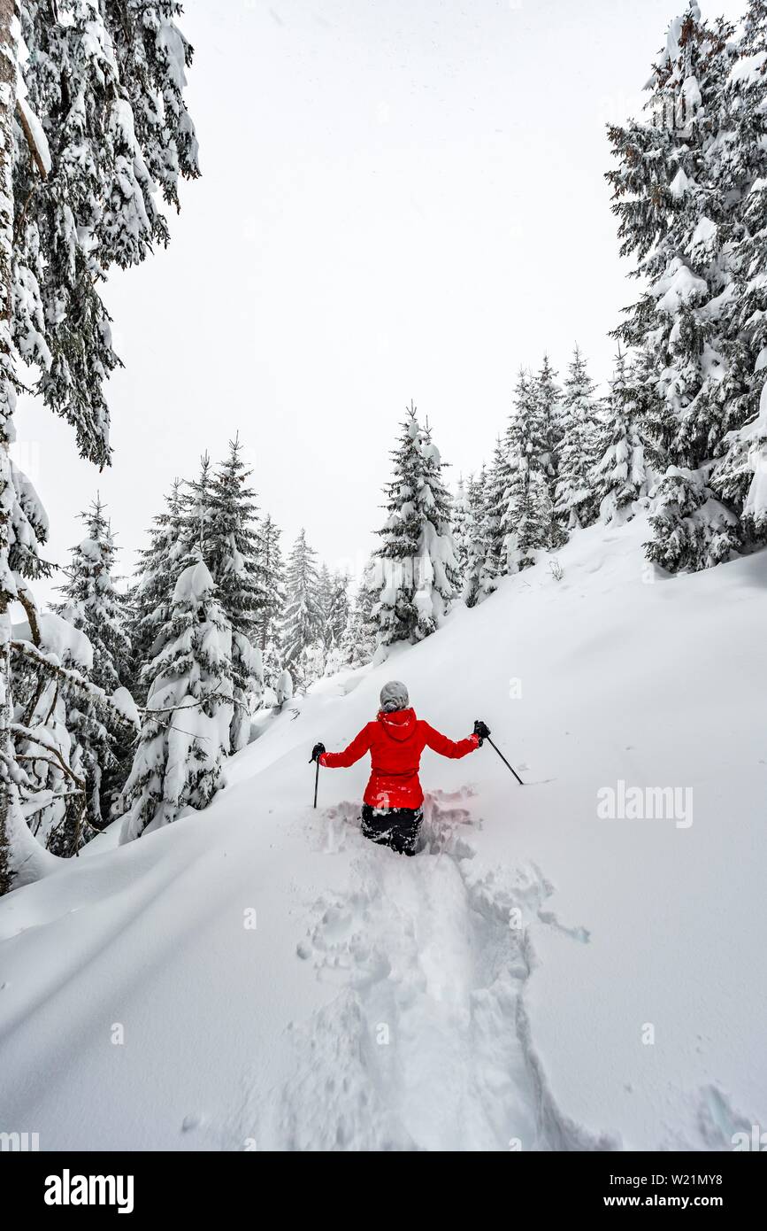 Jeune femme debout dans la neige profonde, la randonnée en hiver, de la neige profonde dans la forêt, Brixen im Thale, Tyrol, Autriche Banque D'Images