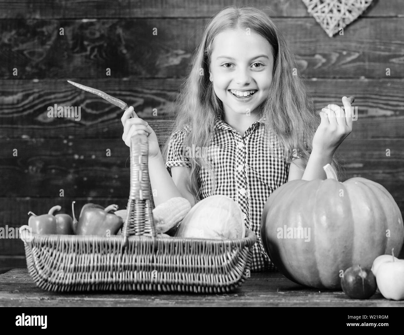 La petite fille profiter de la vie à la ferme. Le jardinage biologique. Kid agriculteur récolte avec fond de bois. Cultiver votre propre nourriture biologique. Girl kid au marché à la ferme avec des légumes bio. Harvest Festival concept. Banque D'Images