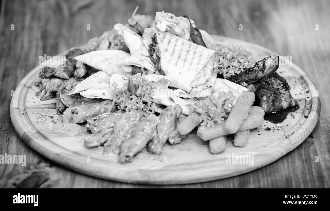 Calories élevé pour le groupe d'amis. De délicieux en-cas savoureux. Les repas au restaurant. Snack pour la bière. Planche de bois avec beaucoup de frites et bâtonnets de poisson viande burrito steak servi avec une salade. Menu snack-bar. Banque D'Images