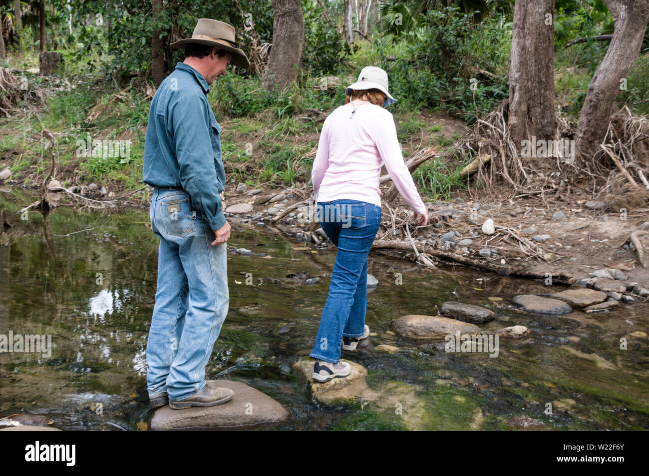 Un couple Australien au-dessus d'une rangée de pierres de gué à travers le Carnarvon Creek dans le Parc National de Carnarvon Gorge en Highlan Banque D'Images