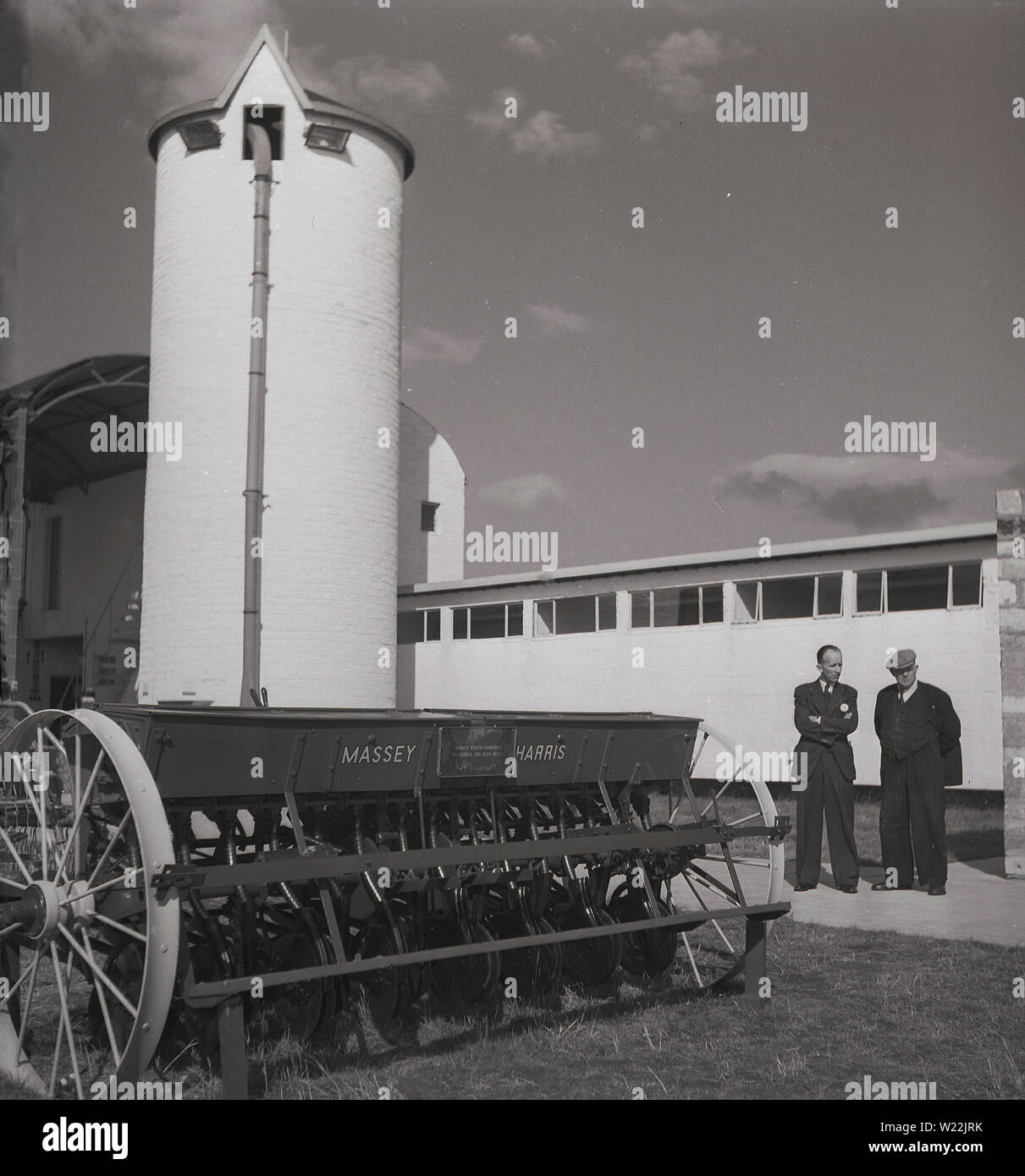 Années 1950, historiques, deux hommes lors d'une foire commerciale agricole Comité permanent par un matériel agricole Massey Harris, d'une combinaison d'engrais et d'voir percer, l'Irlande du Nord. Banque D'Images