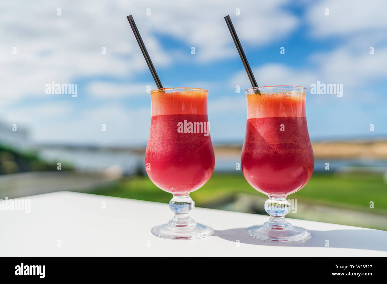 La saine alimentation nettoyer detox jus de concept. Régime végétalien, un jus de tendance. Deux verres de rouge Mélange de légumes, jus de betterave carotte glasses on outdoor cafe ou table de restaurant sur fond de ciel d'été. Banque D'Images