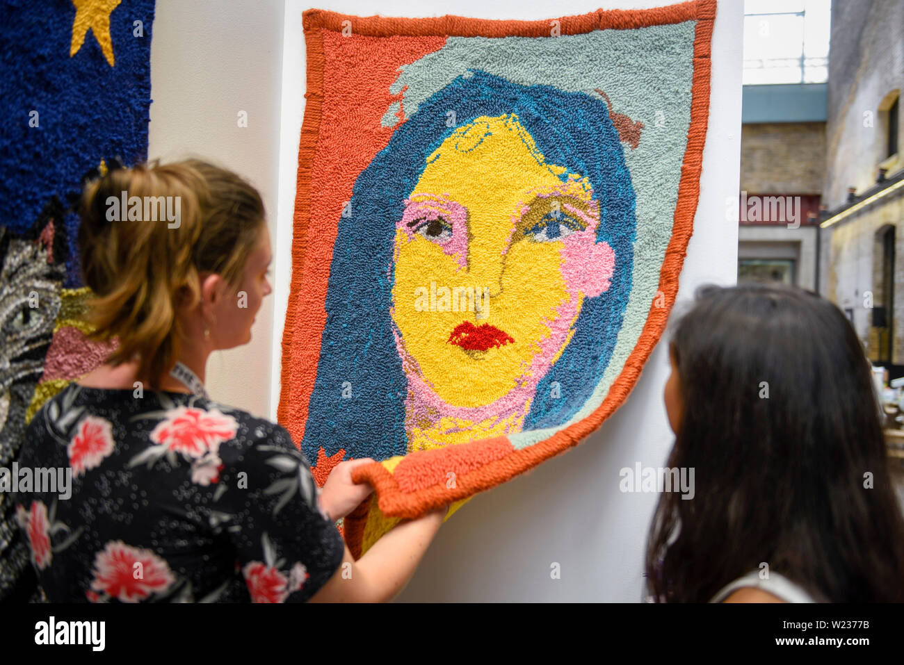 Londres, Royaume-Uni. 5 juillet 2019. Récemment diplômé de Central Saint Martins, artiste Selby Inglefield Hurst (L) montre un travail de Hesse sur la laine à un client potentiel. Jour de l'ouverture de l'autre Art Fair, présenté par Saatchi Art, dans un nouveau lieu de West Handyside Canopy, Kings Cross. La foire est une collection d'œuvres d'artistes émergents et indépendants sélectionnés par un comité d'experts du monde de l'art. Les visiteurs et acheteurs d'avoir l'occasion de rencontrer les artistes de présenter leur travail à la foire qui se déroule 5 au 7 juillet 2019. Crédit : Stephen Chung / Alamy Live News Banque D'Images