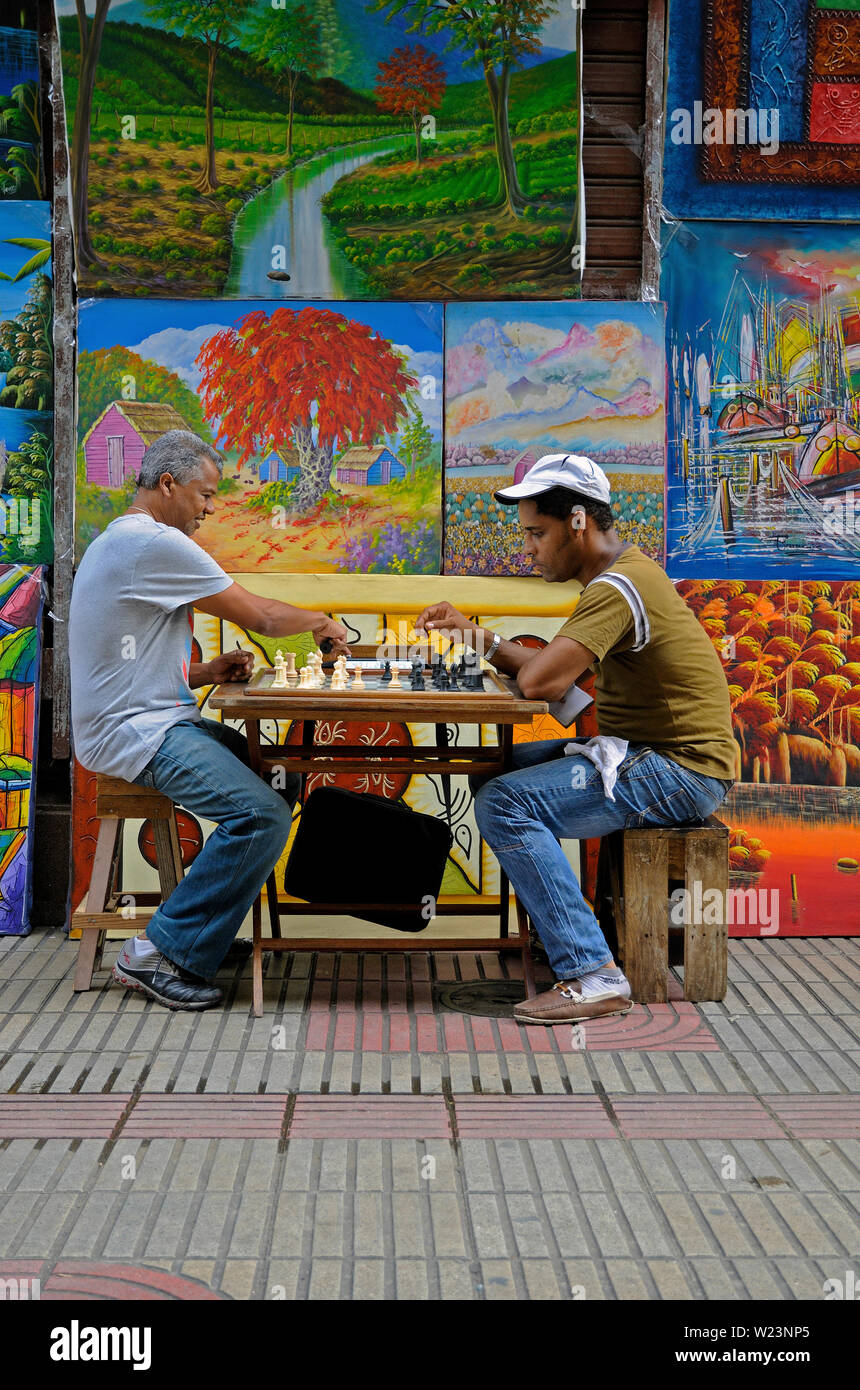 Santo Domingo, République dominicaine - 15 octobre 2013 : deux hommes jouant en avant des expositions d'art d'un peintre sur la calle el conde Banque D'Images
