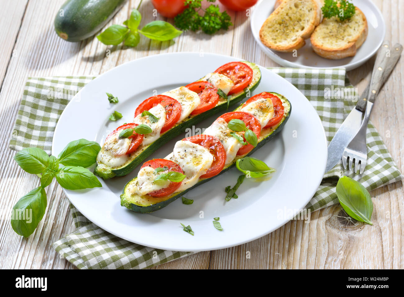 Courgettes farcies et cuites à la tomate, mozzarella et basilic servi avec pain aux herbes Banque D'Images