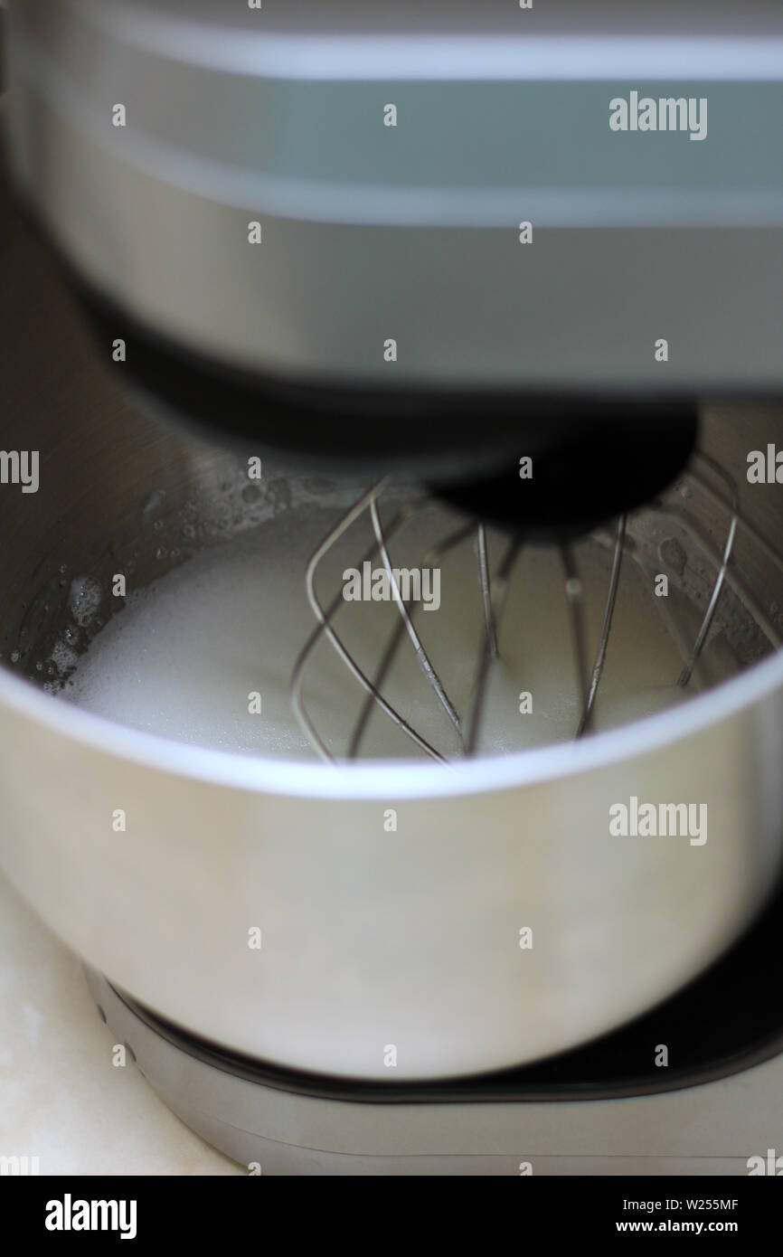 Les blancs d'œufs en fouettant mélangeur de cuisine professionnel dans un restaurant. Close-up fouetté les blancs et le sucre dans un bol mélangeur planétaire de métal. Banque D'Images