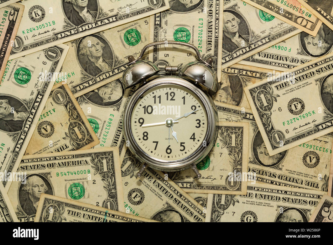Réveil sur un tapis de billets d'un dollar, le temps est argent Photo Stock  - Alamy