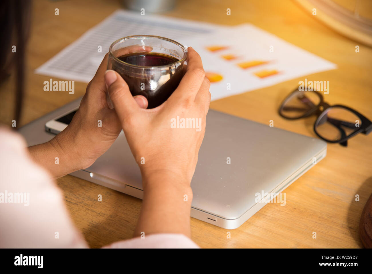 Femme d'affaires en ligne de travail détendue et regarder la navigation sur un ordinateur portable assis dans un bureau à bureau. La femme à l'aide d'une cuillère pendant que se prépare un cof Banque D'Images