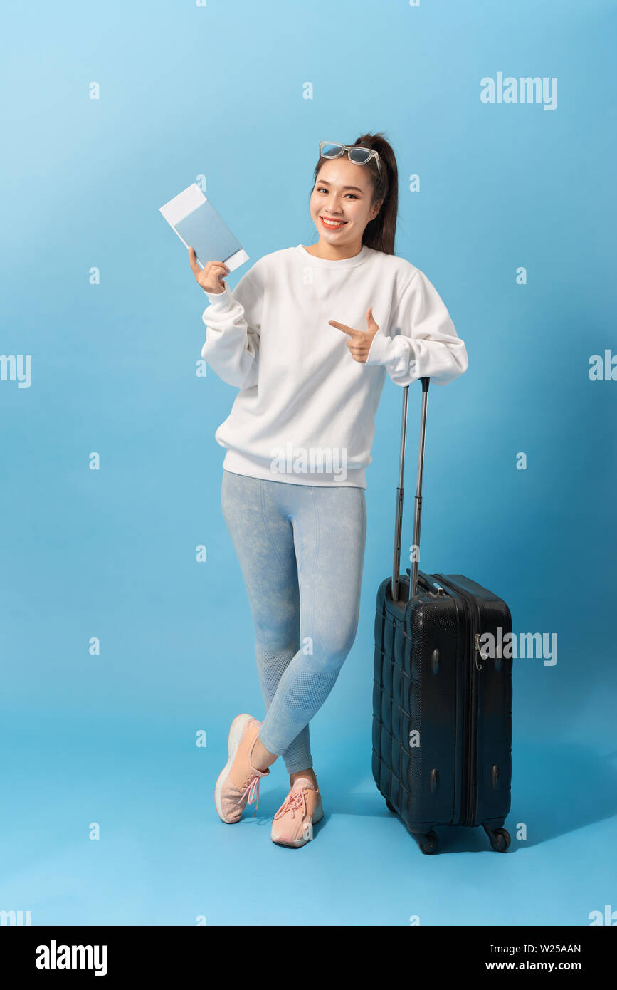 Longueur pleine image of woman in casual clothing la préparation de voyage avec des bagages et des billets sur fond bleu Banque D'Images