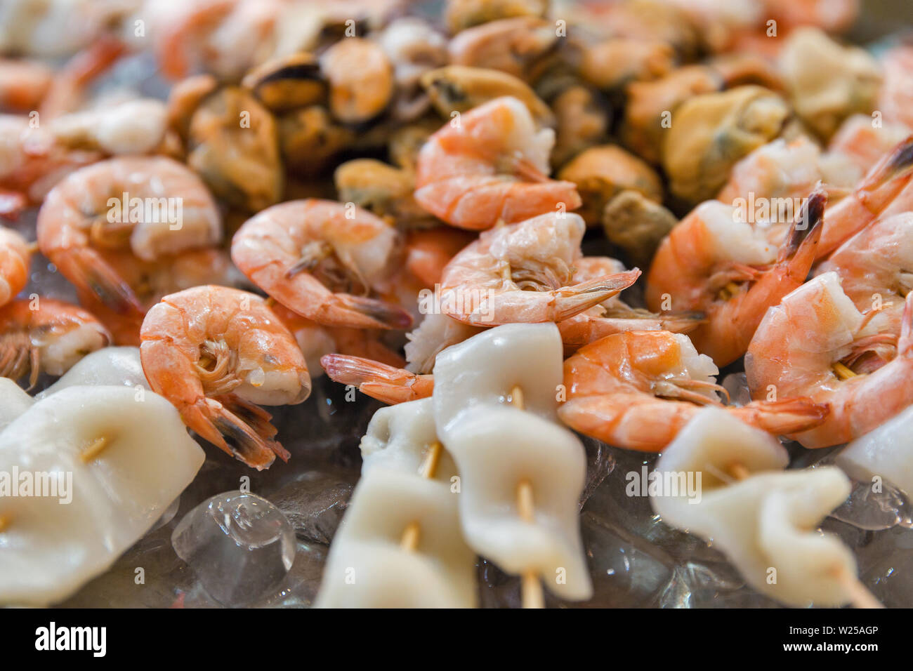 De délicieux fruits de mer brochettes de crevettes appétissant avec des morceaux de calmars et moules, enfilés sur des bâtons en gros plan sur la glace. Banque D'Images