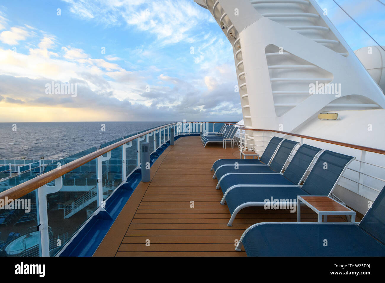 Chaises de salon bleu pour les passagers sur le pont supérieur en bois du navire à côté du pont blanc bâtiments sur l'arrière-plan de la sunset sky avec le cloud Banque D'Images