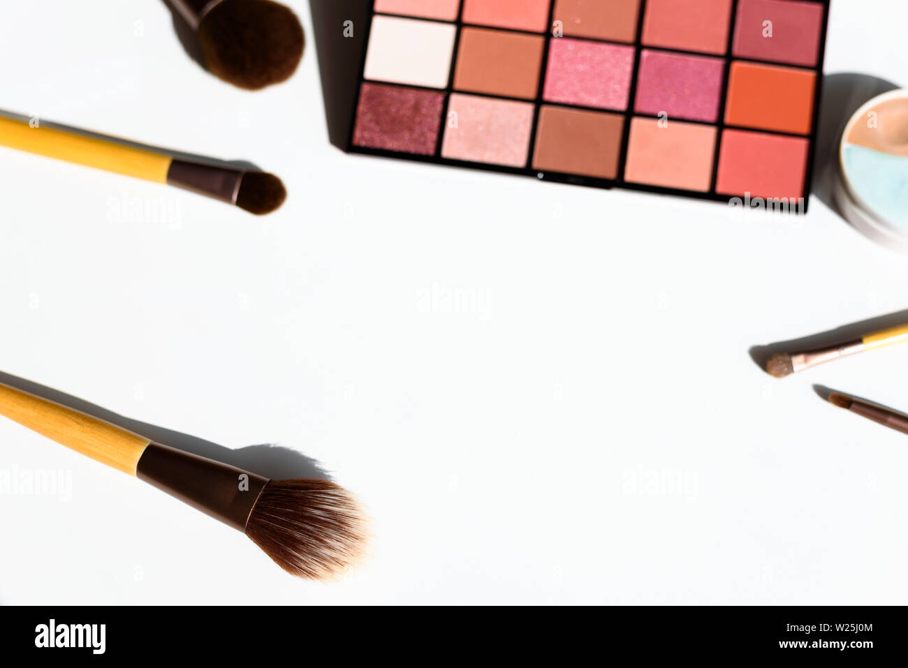 Vue de dessus composent les cosmétiques et les accessoires. Eye shadow palette, dissimulateurs et brosses naturelles avec des manches en bois de bambou. Copie de l'espace dans le milieu. Banque D'Images