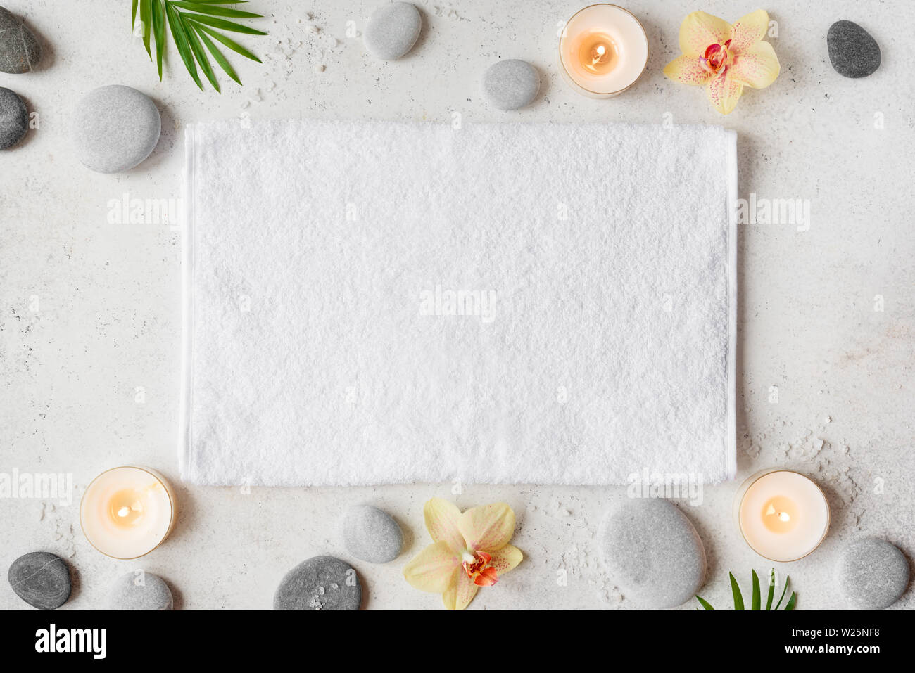 Spa concept sur fond noir en blanc, les feuilles de palmier, des fleurs, des bougies et zen comme grey stones, vue du dessus, copiez l'espace. Banque D'Images