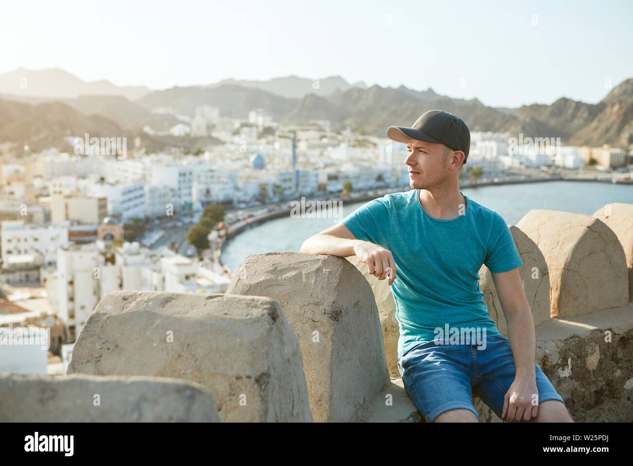 Hôtels à Muscat. Jeune homme contre la vieille ville, mer et montagnes en Oman. Banque D'Images