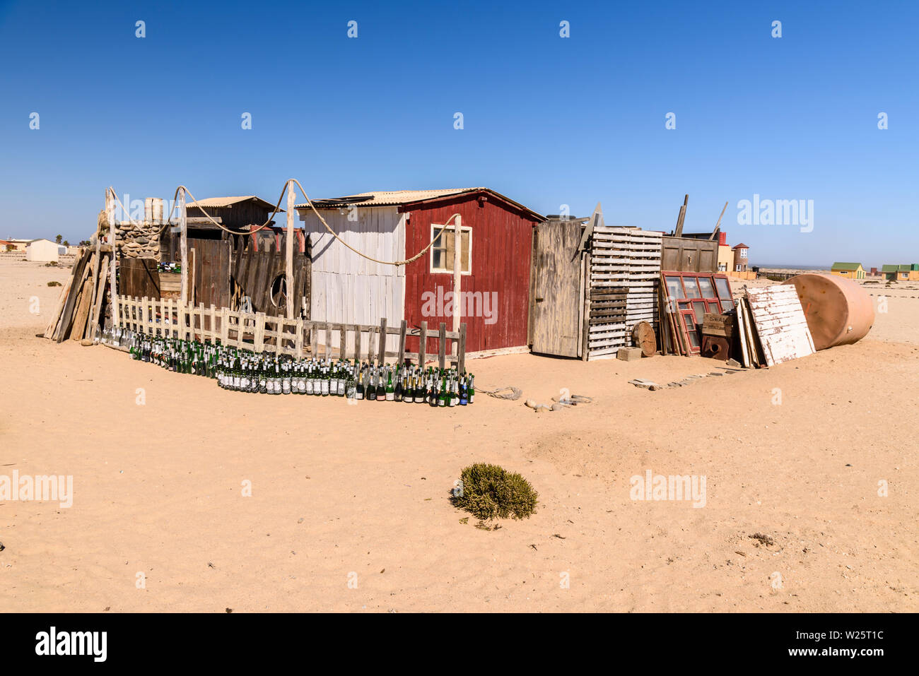 Grand nombre de bouteilles vides de vin et bière à l'extérieur d'un hangar maison ramshackled au bord de la mer, maison de village d'Wlotzkasbake, Skeleton Coast, Namibie Banque D'Images