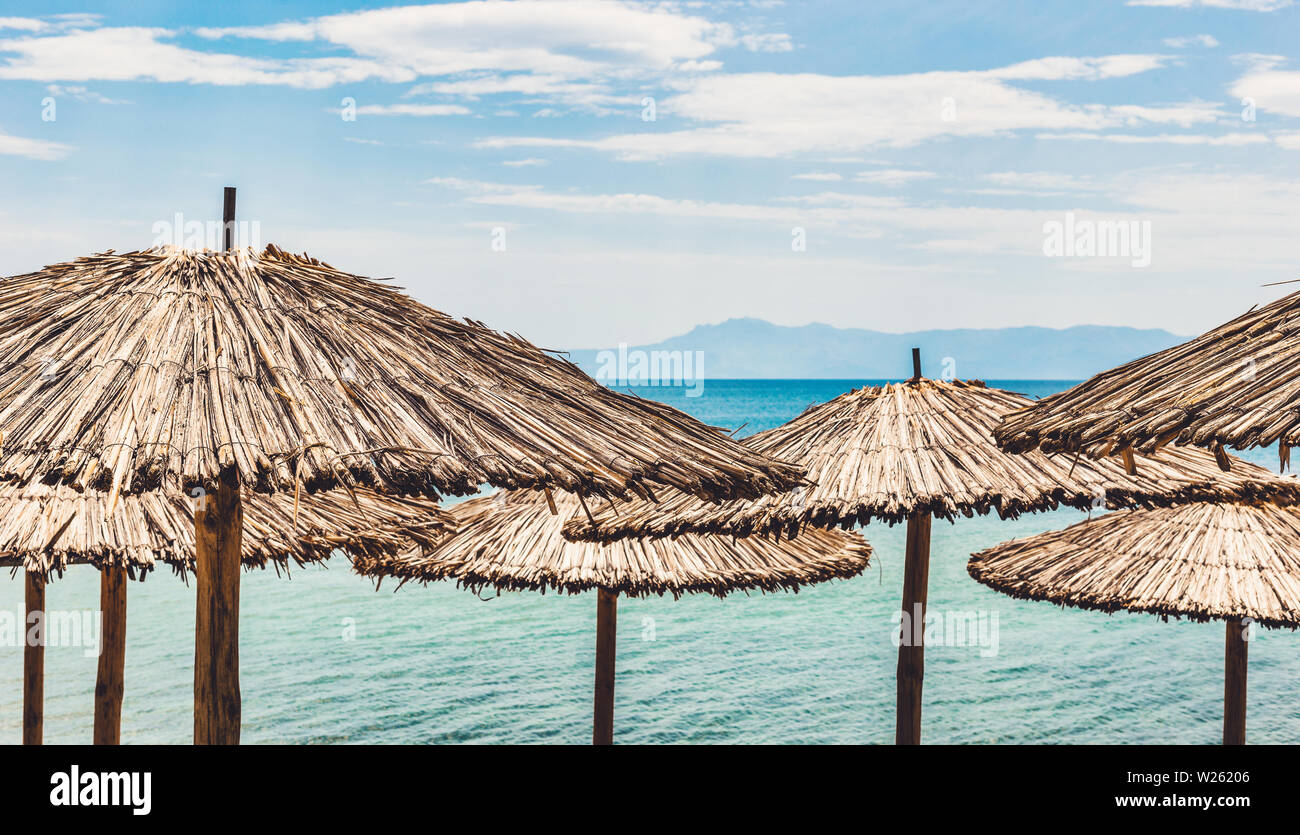 Des parasols de paille sur la plage tropicale avec vue sur la mer sur l'arrière-plan. Beau paysage d'été. Banque D'Images