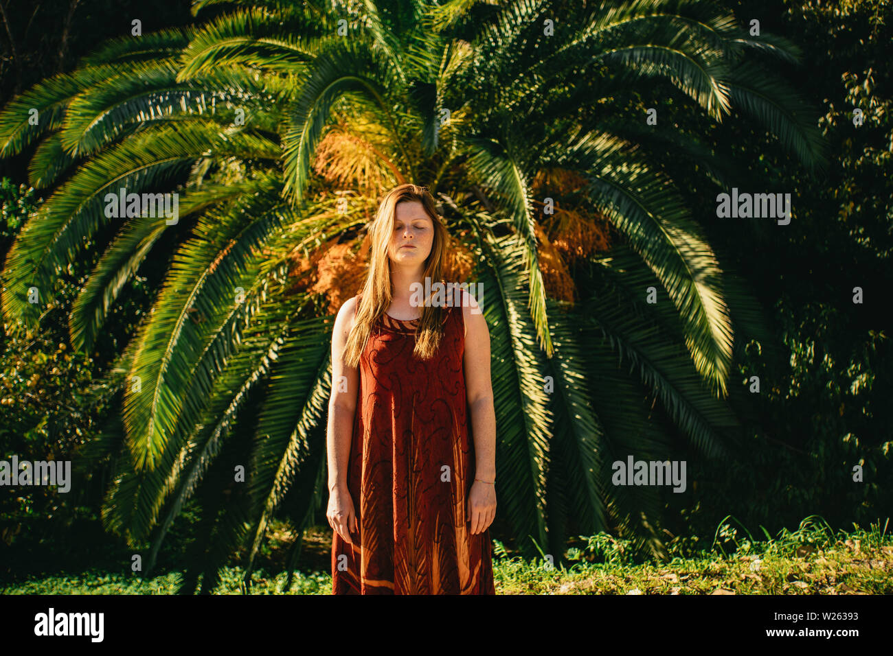 Attractive young woman standing in front of a palm tree tropicales dans les jardins de la Concepcion Historical-Botanical à Malaga Banque D'Images