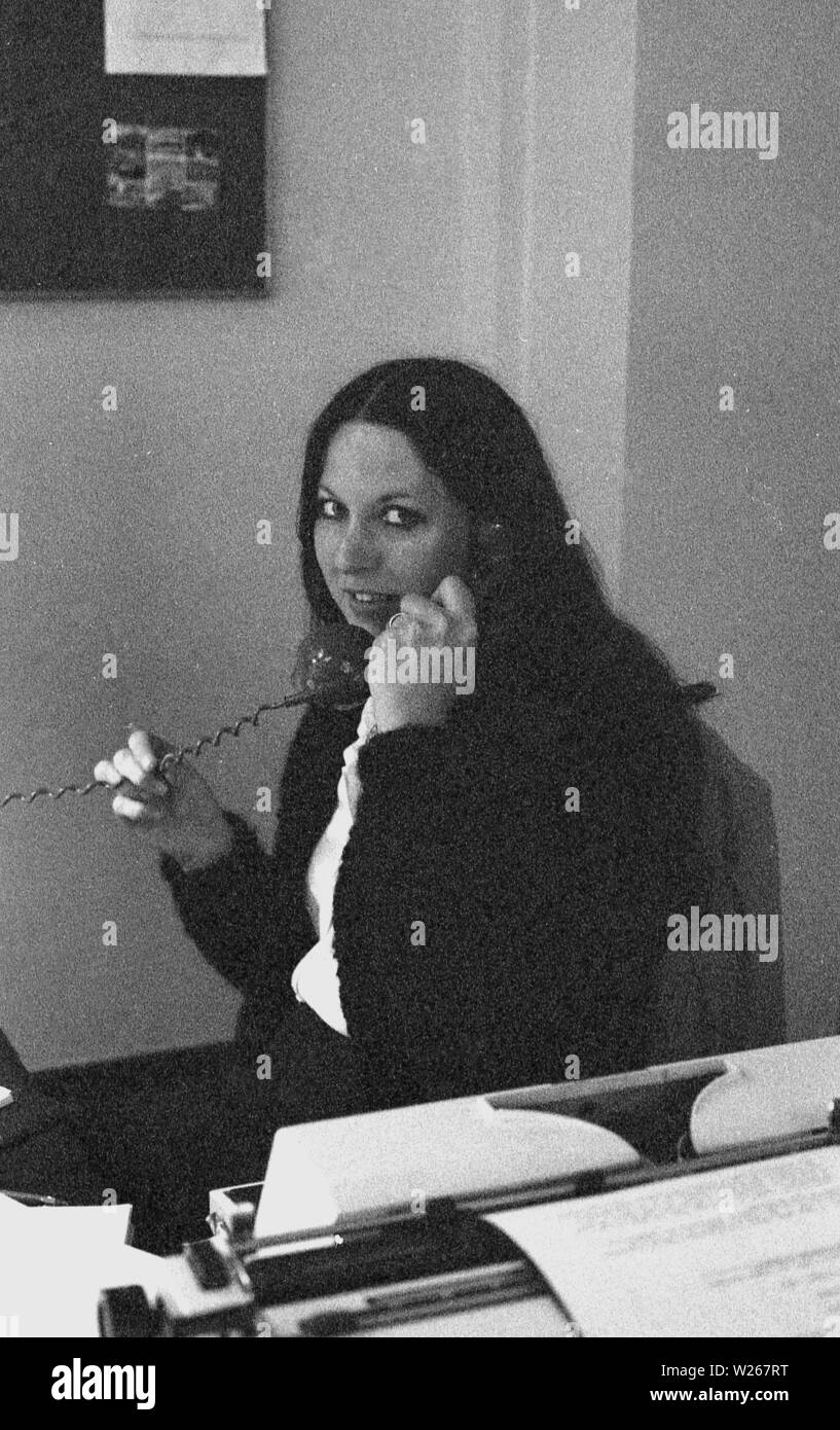 Années 1970, historiques, female office worker à son bureau parlant au téléphone à côté d'une machine à écrire, England, UK. Banque D'Images