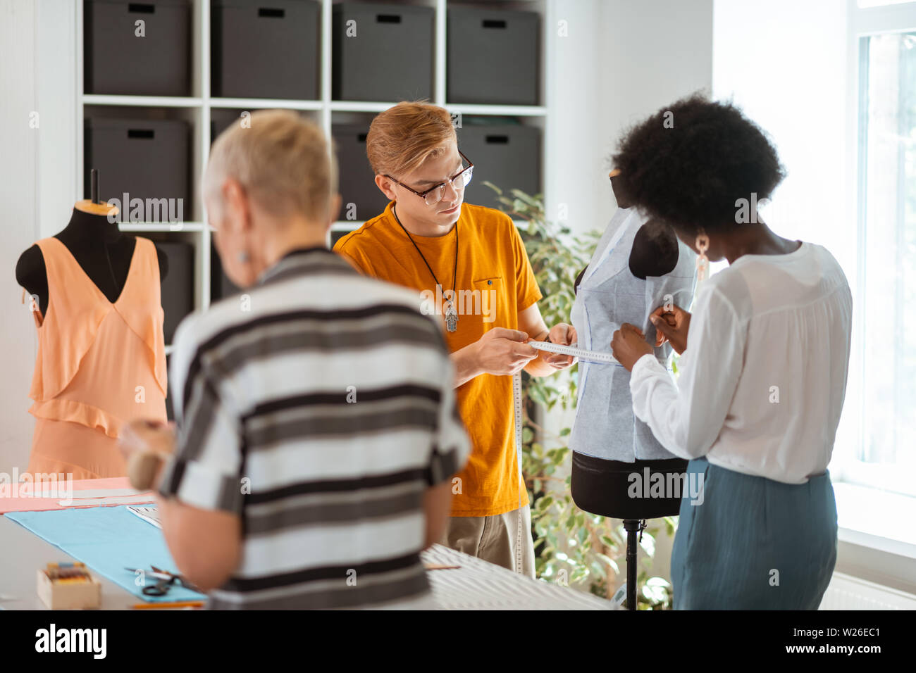 Collègue masculin. Retour Voir portrait de deux femmes fashion designers travaillant ensemble avec leur collègue masculin dans un studio Banque D'Images