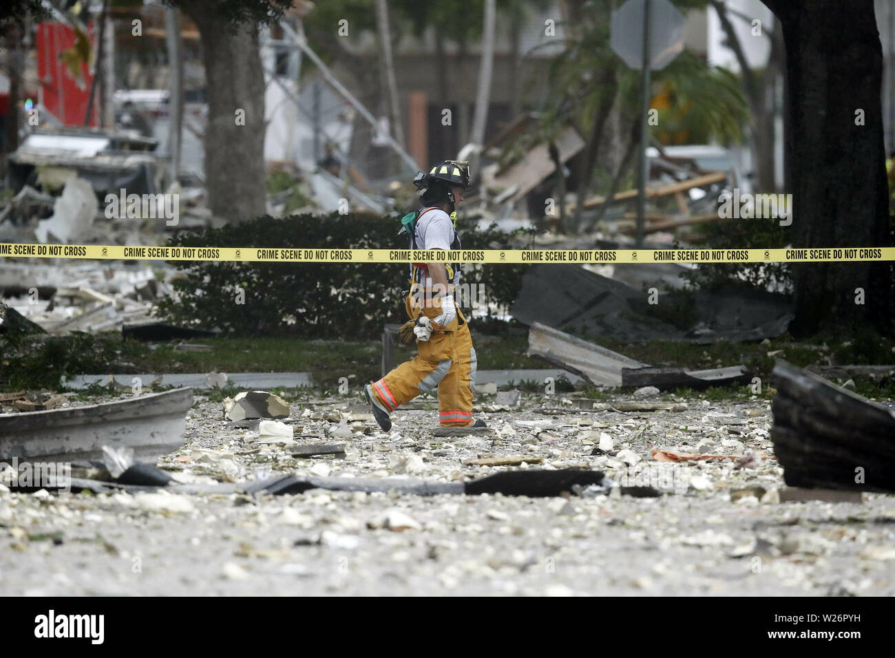 Un pompier de promenades à travers les vestiges d'un bâtiment après une explosion le Samedi, Juillet 6, 2019, en plantation, en Floride, plusieurs personnes ont été blessées après un restaurant Pizza a explosé dans le sud de la Floride shopping plaza samedi, selon la police. Le restaurant a été détruit, et les entreprises voisines ont été endommagées. (AP Photo/Brynn Anderson) Banque D'Images