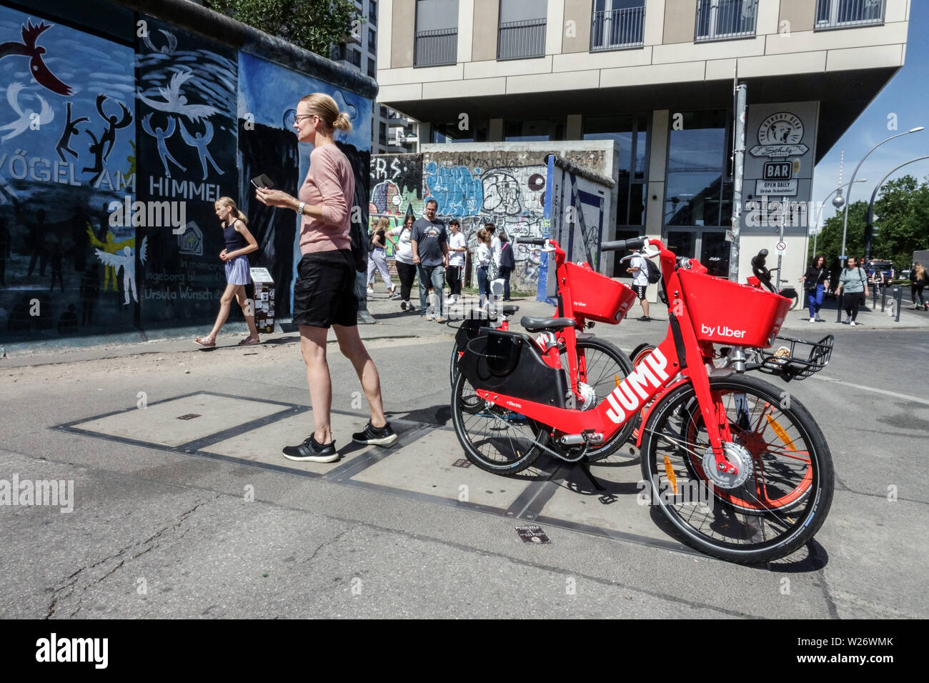 Location vélo électrique par Uber à côté est mur de Berlin Allemagne Touristes Banque D'Images