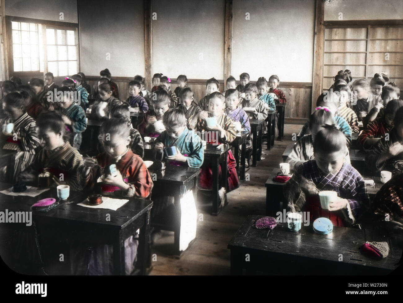 [ 1900 - Japon ] Les élèves de l'école élémentaire des femmes - japonais de l'école élémentaire de manger dans une salle de classe. Cette image fait partie de 'la vie scolaire des jeunes Japon" (n° 9), une série publiée par le photographe japonais Kozaburo Tamamura au début des années 1900 (la fin de l'ère Meiji). 20e siècle vintage lame de verre. Banque D'Images