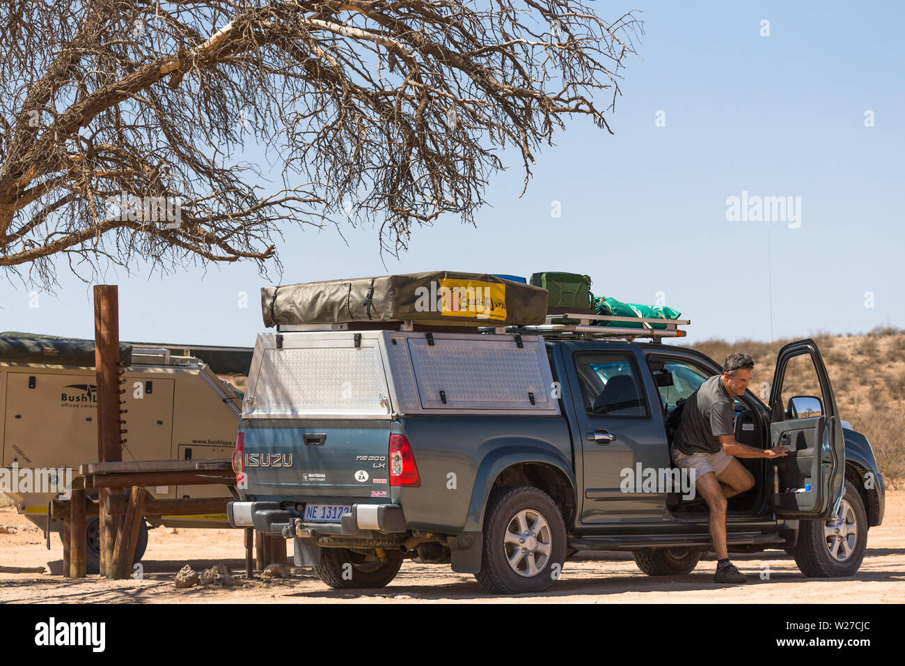 Homme ou touristiques sortir d'un 4x4 off road aventure terrestre véhicule à un arrêt de repos ou en pique-nique du parc transfrontalier de Kgalagadi, Afrique du Sud Banque D'Images
