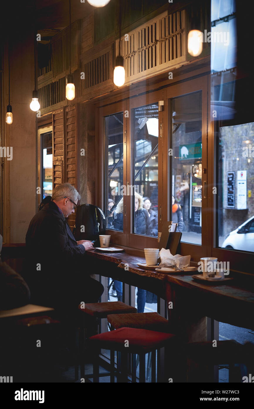Londres, UK - février 2018. Un homme assis dans un café à Borough Market. Banque D'Images
