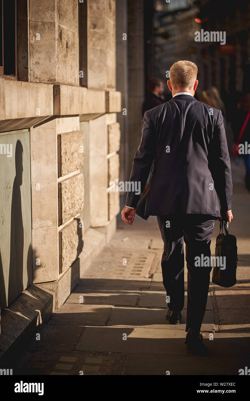 Londres, UK - Février, 2019. Un homme d'affaires marcher sur un trottoir de la ville, le célèbre quartier financier de Londres. Banque D'Images