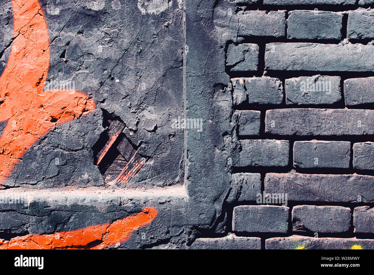 Grunge, gris foncé, fond rugueux avec de la peinture orange. Mur en brique sur la rue Banque D'Images
