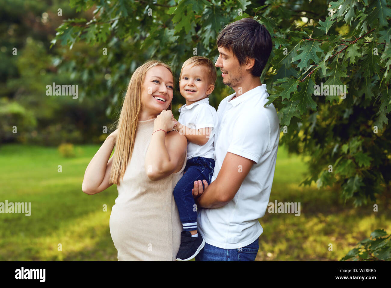 Famille heureuse ensemble dans le parc d'été. Mère, père et fils de l'enfant dans la nature. Banque D'Images