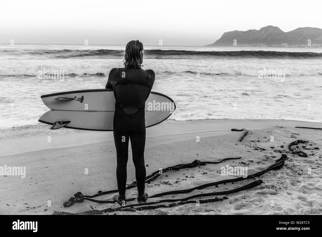 Un surfeur de St James sur Danger Beach envisage de retourner dans la mer tout en regardant une autre série de vagues sur la péninsule du Cap, Afrique du Sud Banque D'Images