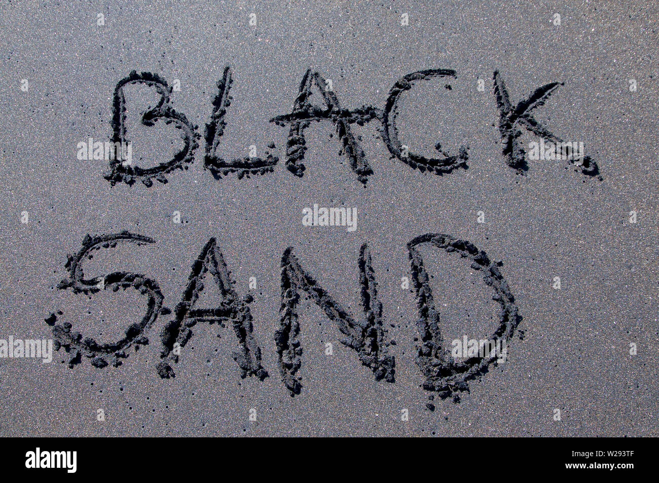 L'inscription de sable noir dessiné sur une plage de sable noir près de Canggu, Bali - Indonésie Banque D'Images
