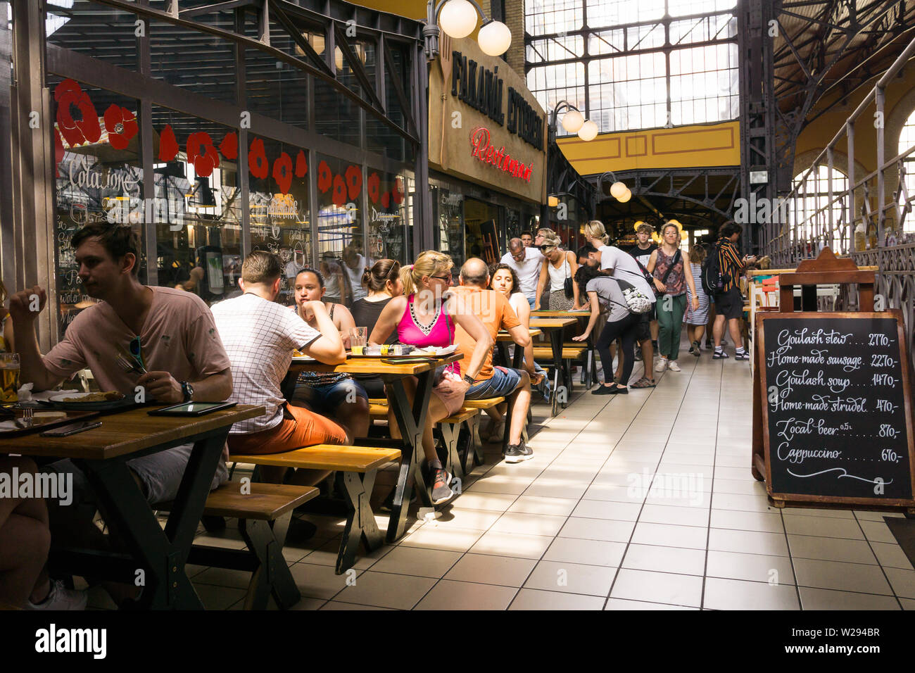 Les touristes ayant le déjeuner dans un restaurant à la Grande Halle à Budapest, Hongrie. Banque D'Images