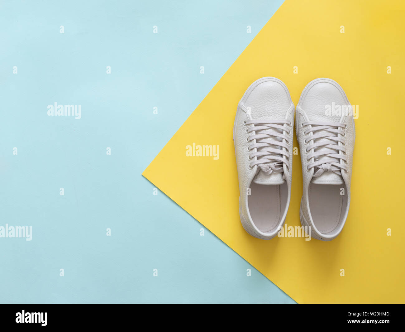 Chaussures en cuir blanc et bleu sur fond jaune. Paire de chaussures de sport blanc la mode à la mode ou des chaussures avec copie espace pour texte sur fond coloré. Frais généraux d'un nouveau livre blanc shot tennis.Télévision lay Banque D'Images Chaussures en cuir blanc et bleu sur fond jaune. Paire de chaussures de sport blanc la mode à la mode ou des chaussures avec copie espace pour texte sur fond coloré. Frais généraux d'un nouveau livre blanc shot tennis.Télévision lay Banque D'Images