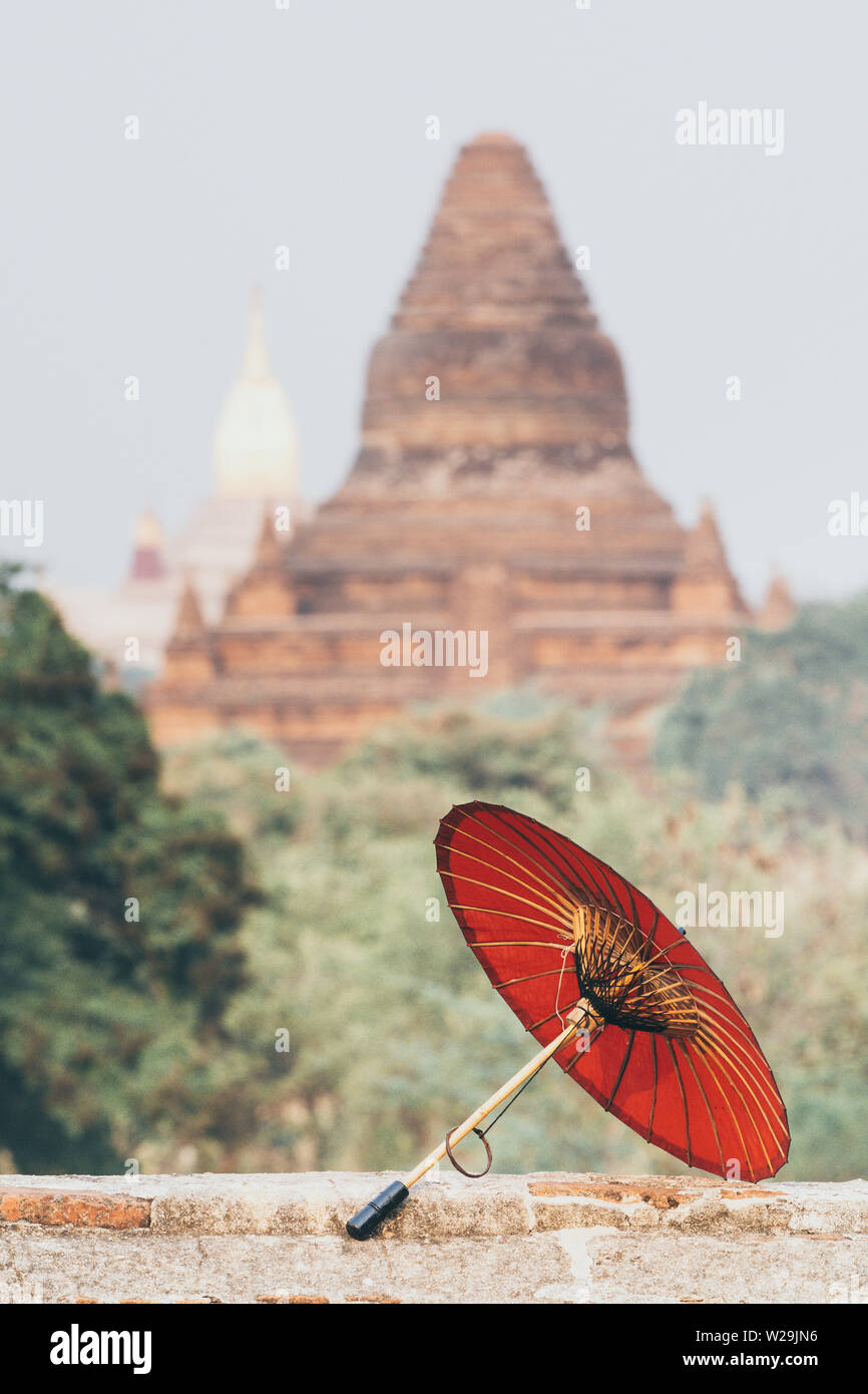 Birman traditionnel parapluie rouge avec Ananda temple le contexte de Bagan, Myanmar. Orientation verticale Banque D'Images