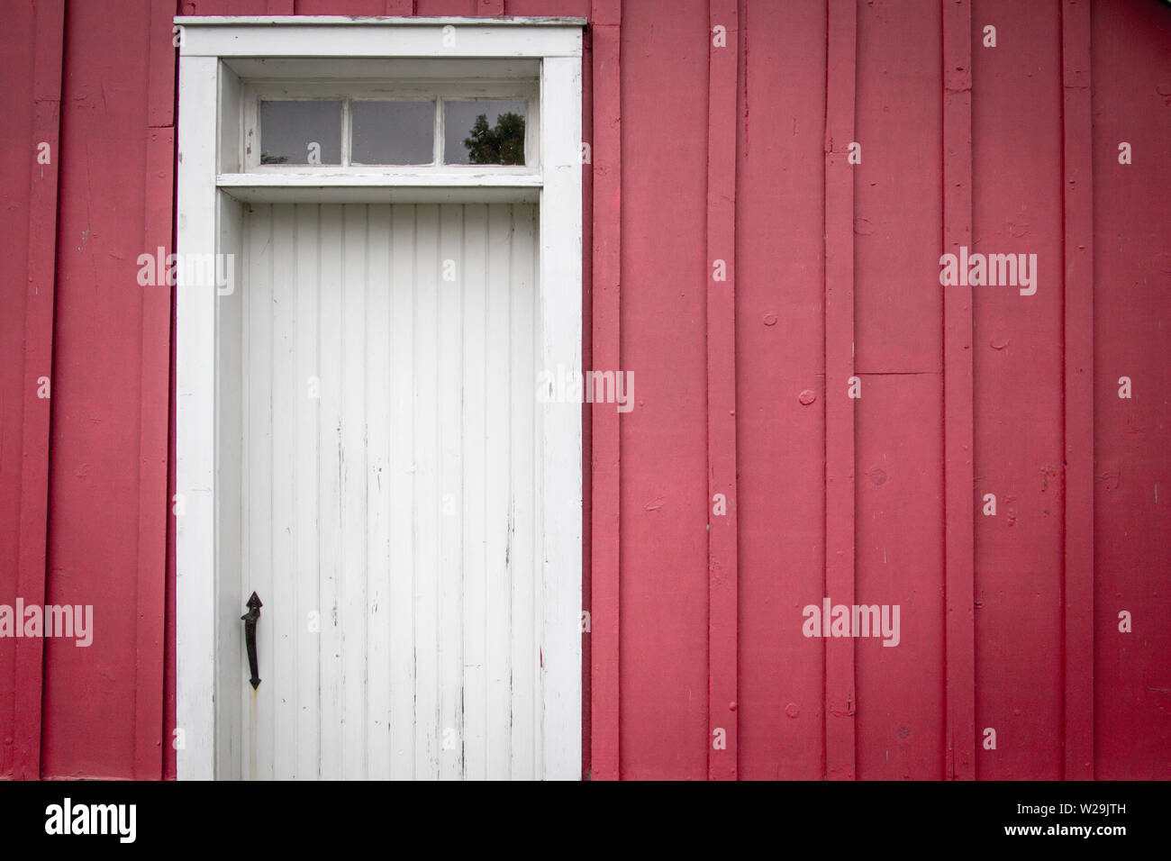 Grange rouge l'extérieur. Extérieur d'un vieux mur de la grange en bois rouge avec porte latérale et de copie dans l'espace orientation horizontale. Banque D'Images