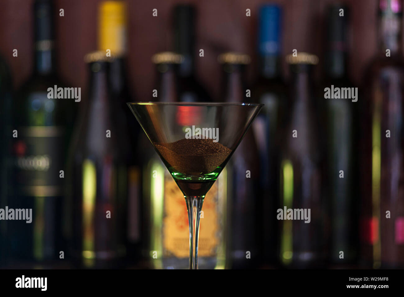 Close up concept photo de marc de café dans un verre à cocktail sur un comptoir de faible lumière avec des bouteilles d'alcool dans l'arrière-plan. Banque D'Images
