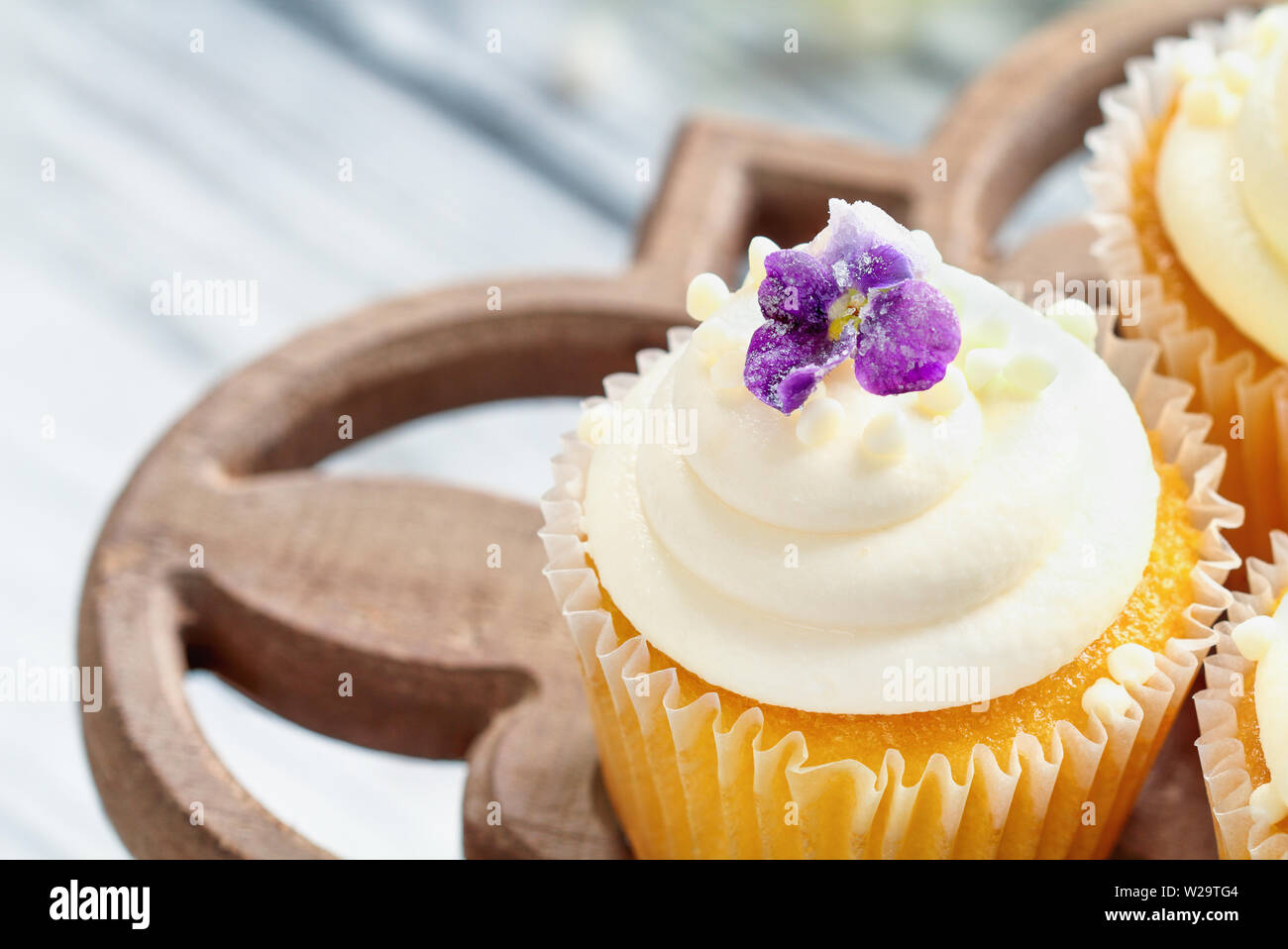 Belle vanilla cupcakes avec glaçage buttercream décoré de fleurs violet enrobé. Focus sélectif avec arrière-plan flou. Banque D'Images