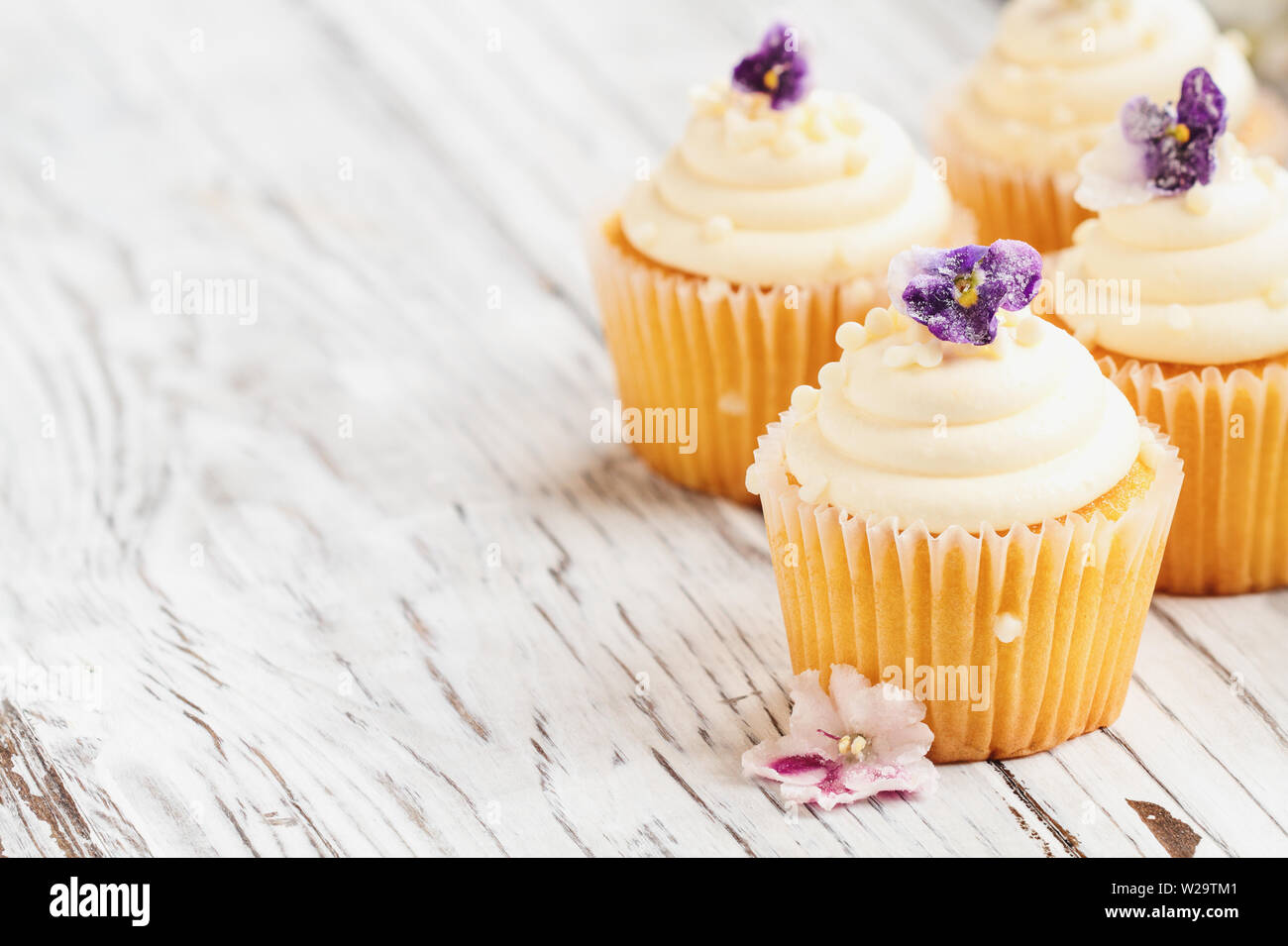 Belle vanilla cupcakes avec glaçage buttercream décoré de fleurs violet enrobé. Focus sélectif avec arrière-plan flou. Banque D'Images
