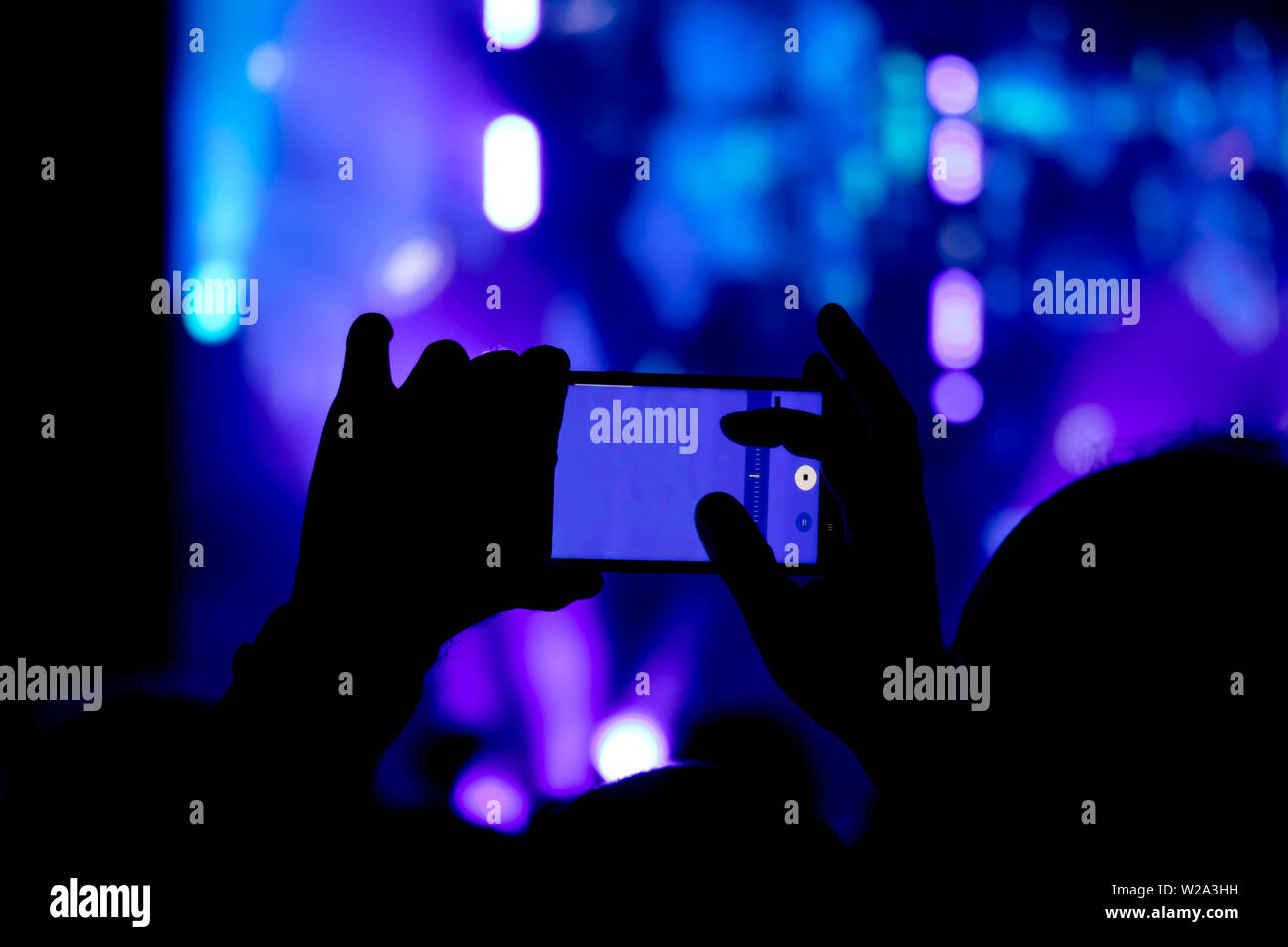 La collecte de mémoire numérique perd de capacité d'être présent, silhouette d'un homme part la prise de concert avec son smart phone Banque D'Images