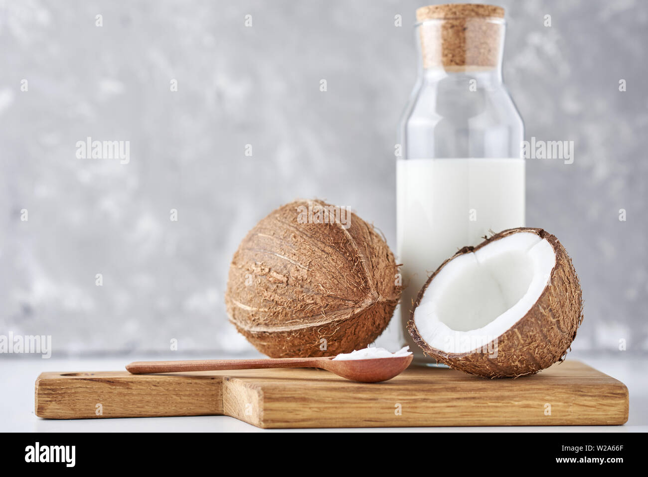 Le Lait De Coco En Bouteille En Verre Et De Coco Fraîche Avec La Moitié Sur  Fond Gris Photo Stock - Alamy
