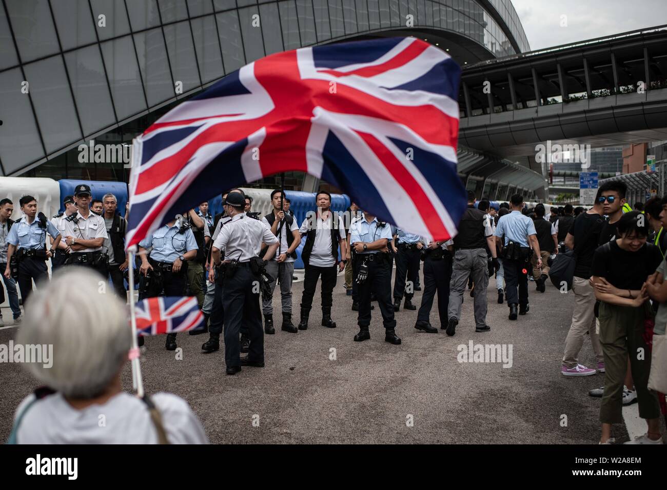 Les vagues un manifestant le drapeau britannique devant un groupe d'agents de police au cours de la manifestation contre la loi sur l'extradition vers la Chine. Banque D'Images