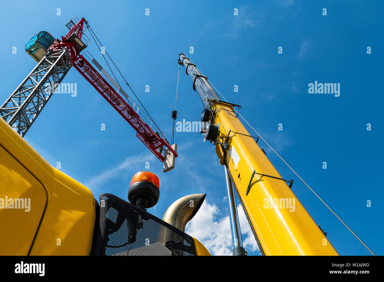 Assemblée générale de grue à tour. L'installation du dispositif de levage. Placer un contrepoids en béton par des bras télescopique de levage mobile jaune machine. Ciel bleu. Banque D'Images