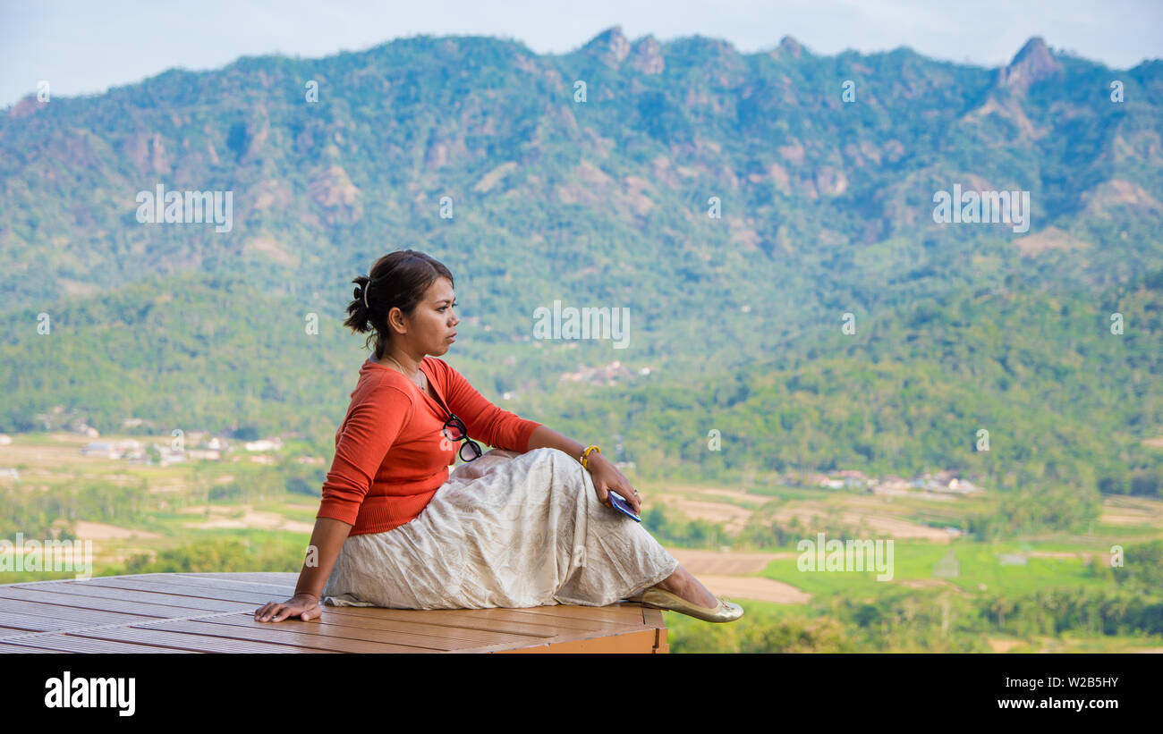 Young Asian woman sitting et regardant par la campagne pittoresque du centre de java, en Indonésie. Banque D'Images
