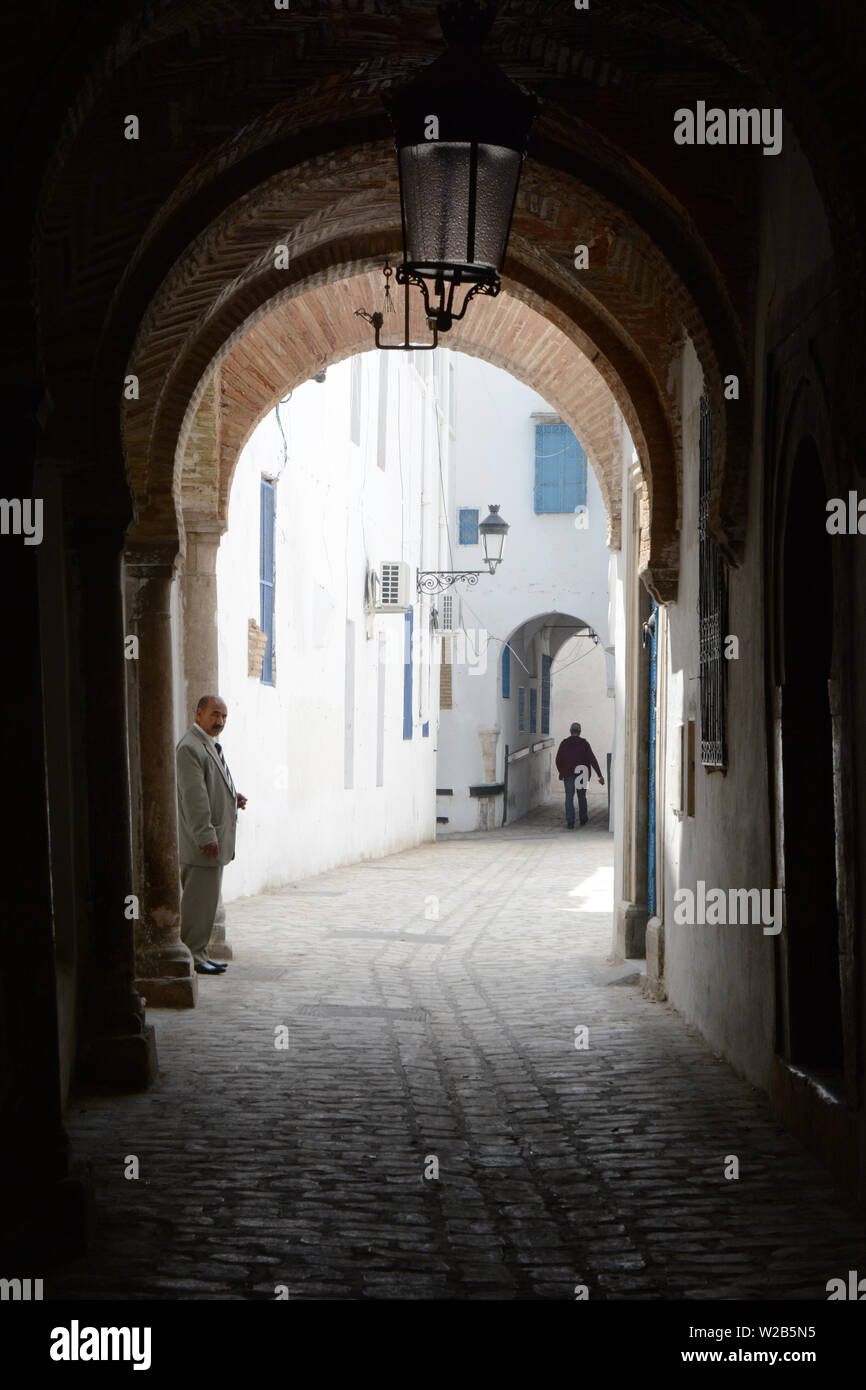 Un vieux homme tunisien permanent, sous un plafond voûté dans une ruelle piétonne dans la Médina de Tunis, Tunisie. Banque D'Images