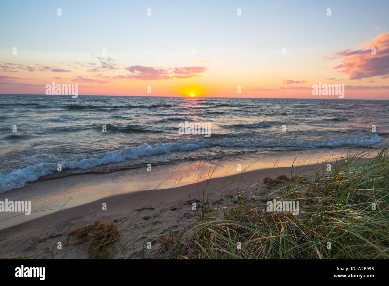 Horizon coucher du soleil se reflète sur les eaux bleues du Lac Michigan comme les vagues déferlent sur la plage. Hoffmaster State Park. Muskegon (Michigan). Banque D'Images