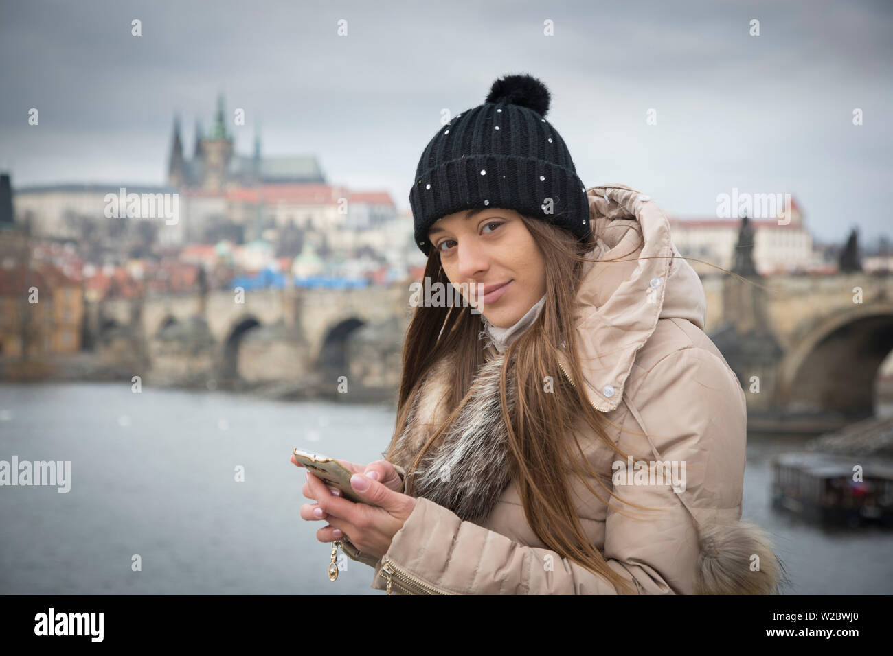 Jeune femme avec smart phone par la Vltava, Prague, République tchèque (MR) Banque D'Images