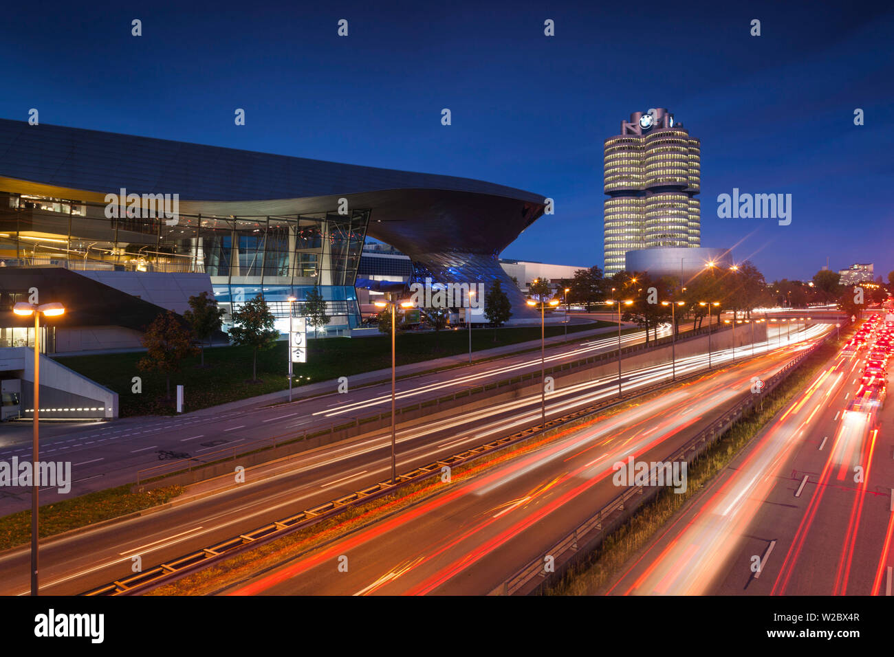 Germany, Bavaria, Munich, BMW Welt showroom de l'entreprise, siège de l'entreprise BMW et BMW Museum avec trafic du soir Banque D'Images